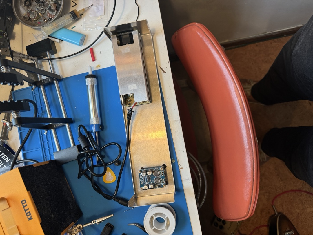 The amp chassis on the bench beside the soldering station