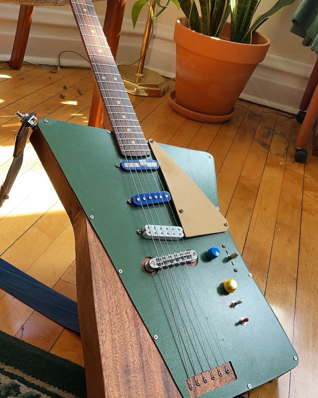 The Camilo standing in the light, showing its three pickups and angular green body