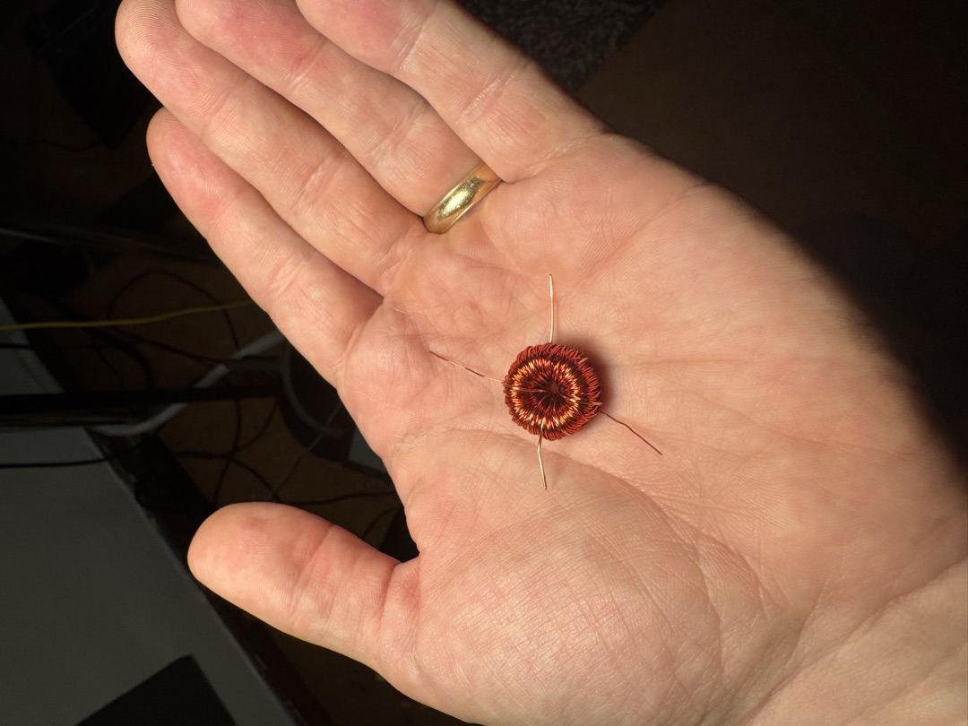 A hand-wound transformer, small enough to sit in a palm