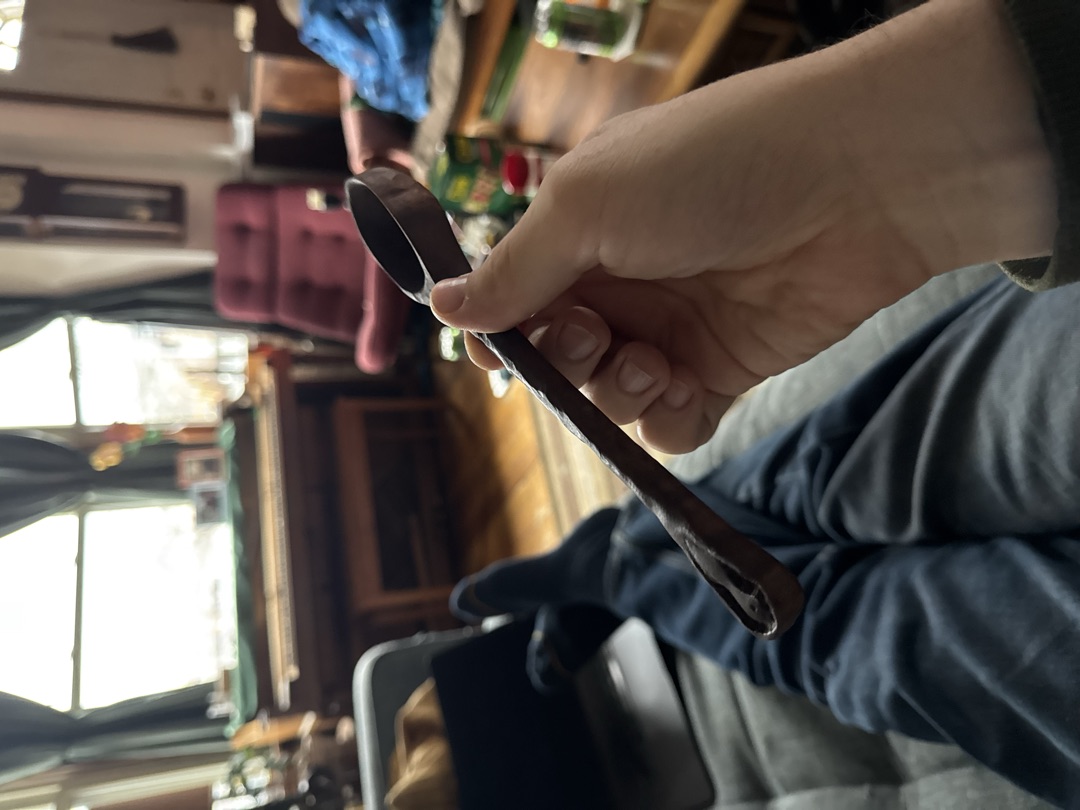 The finished spoon, darkened, held up in the living room